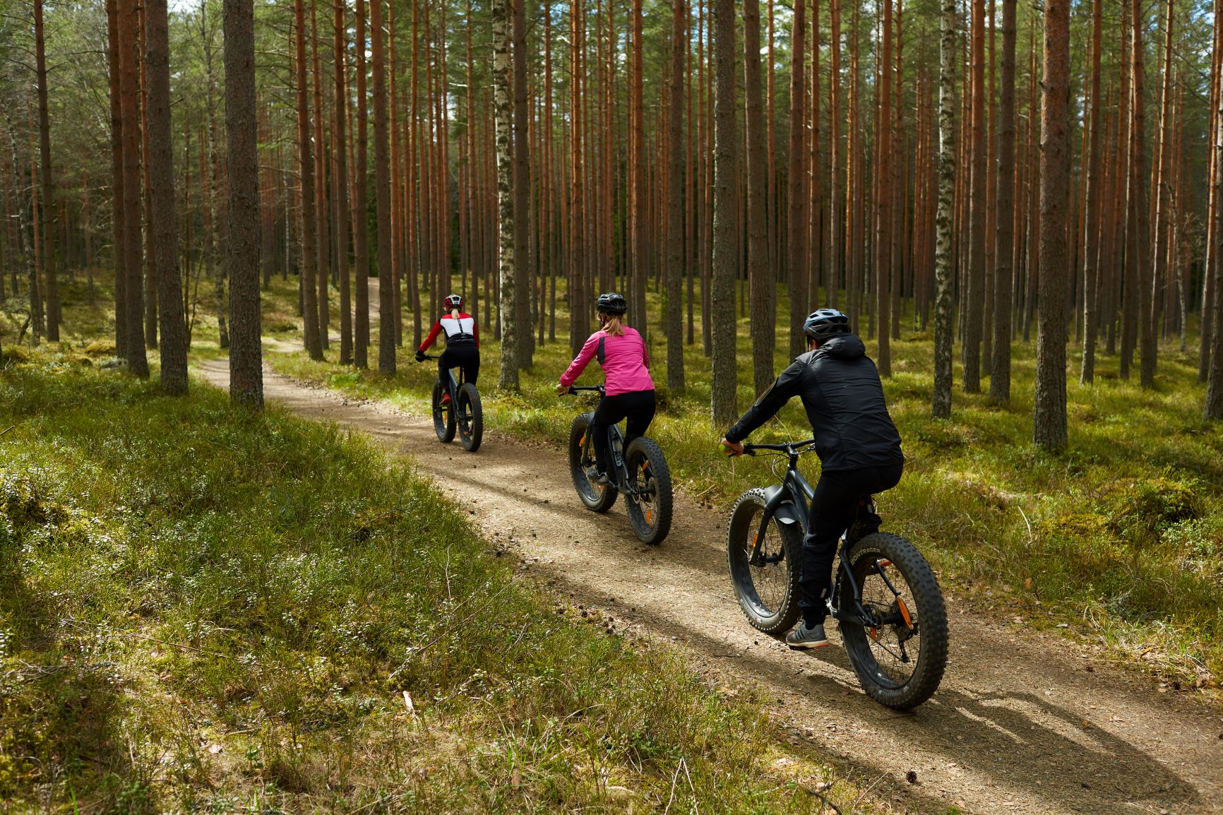 Ihmisiä metsässä fatbikella