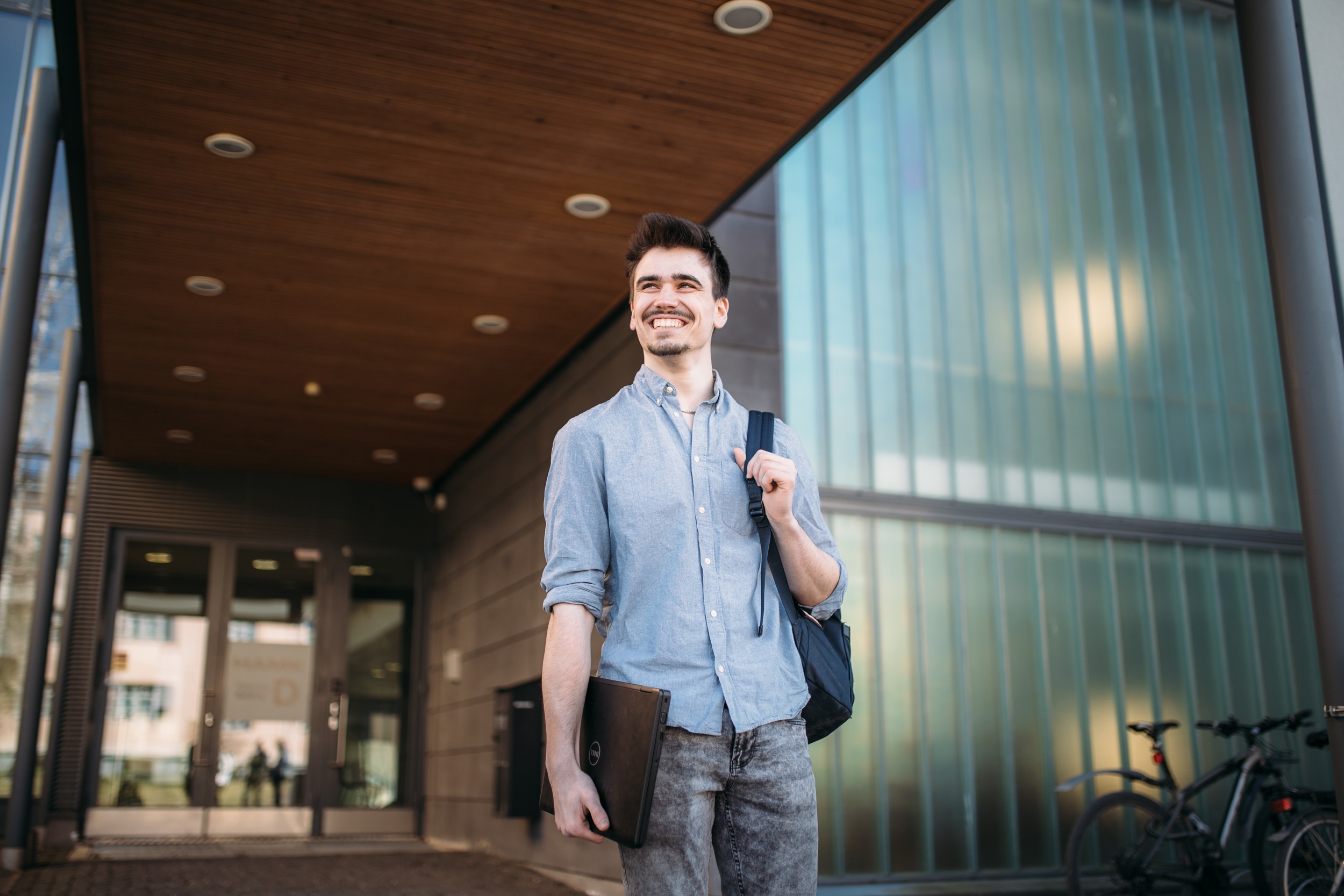 A guy looking left and smiling while walking in a corridor.