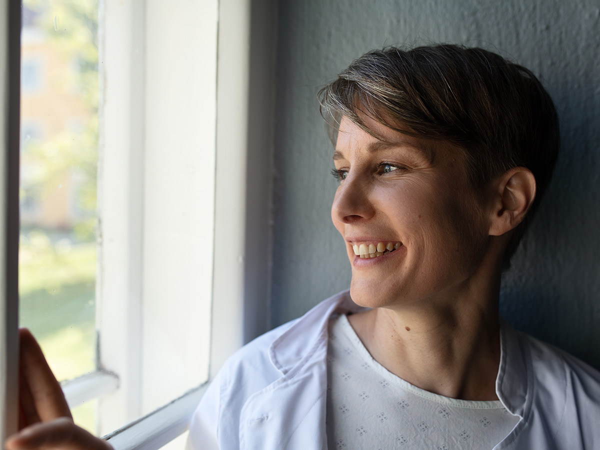 A woman looks out of the window and smiles.