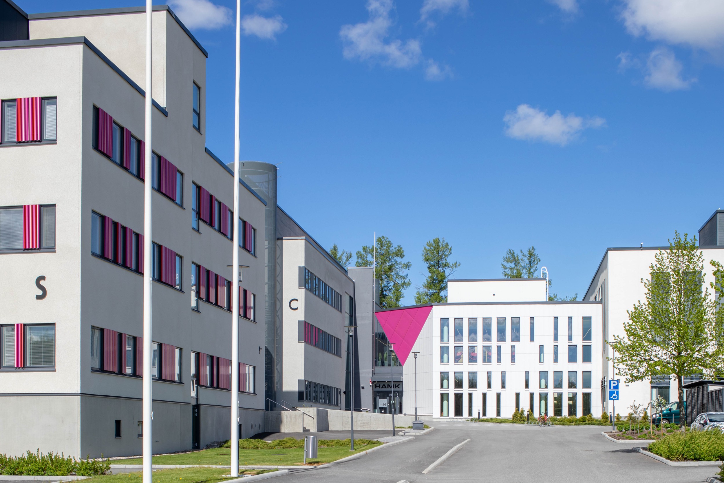 The S and C buildings of the Hämeenlinna University School Centre. The buildings are white, multi-storey and have pink accents on the window frames. 