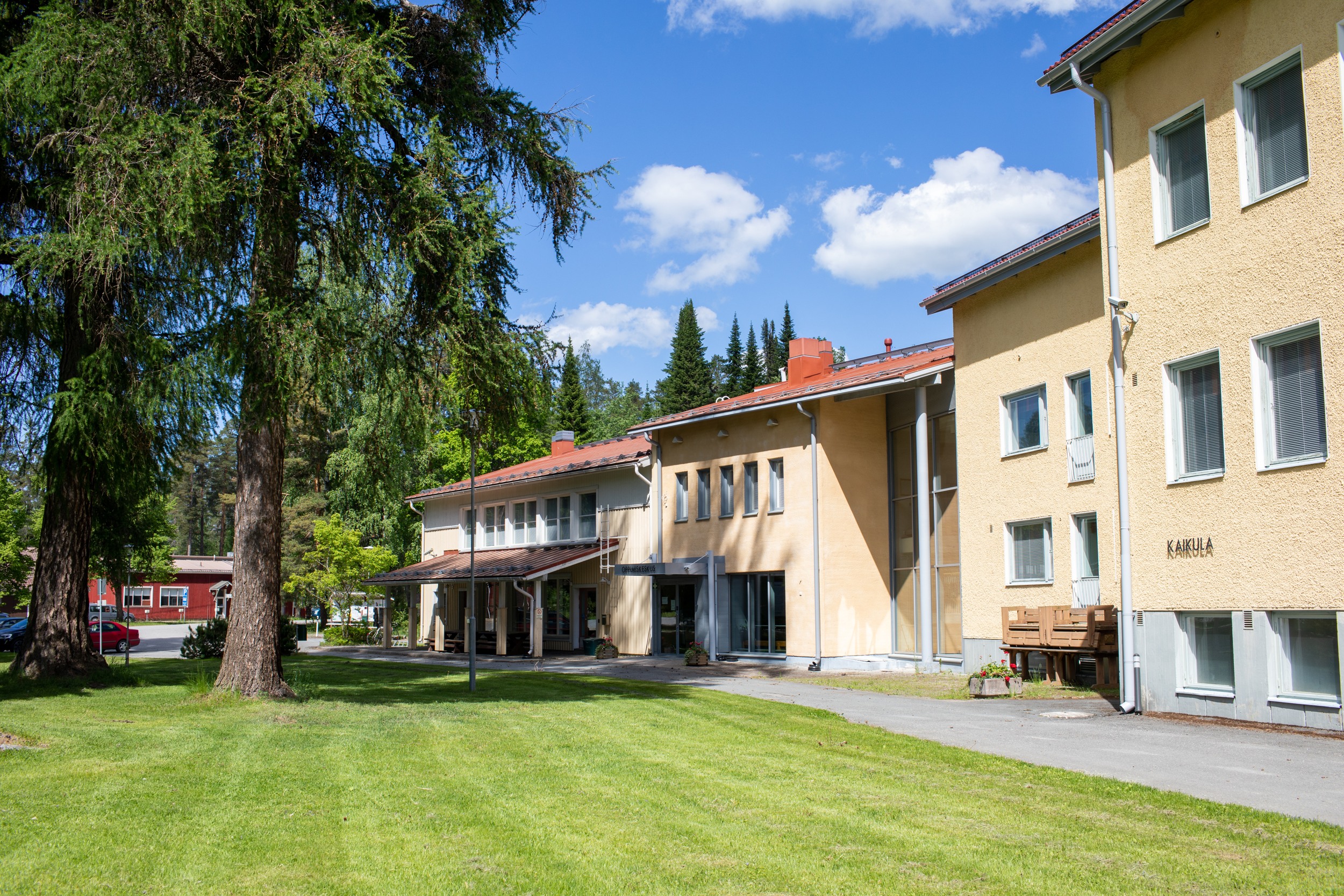 Evo Campus Centre. A light cream-coloured building with a red roof. Green grassy field in the foreground. 