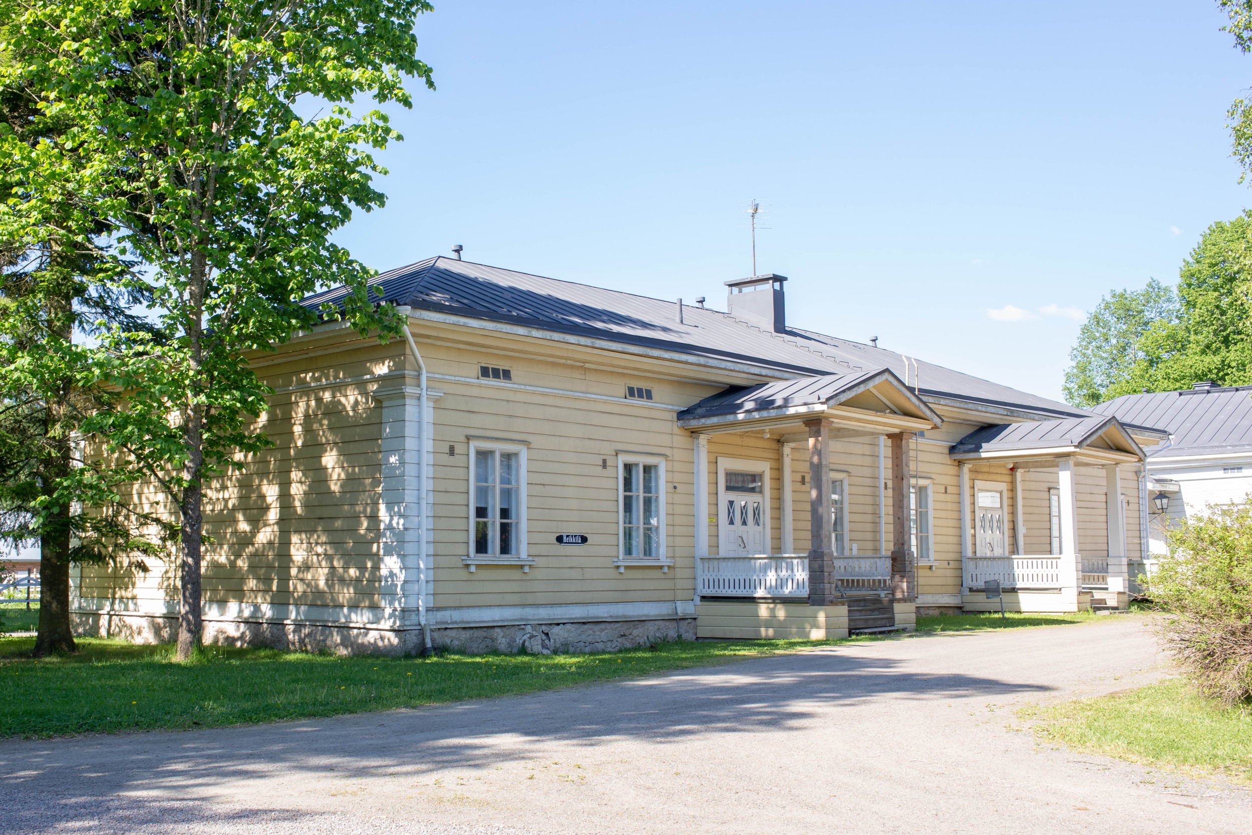 An old yellow wooden building in Mustiala on a sunny day.