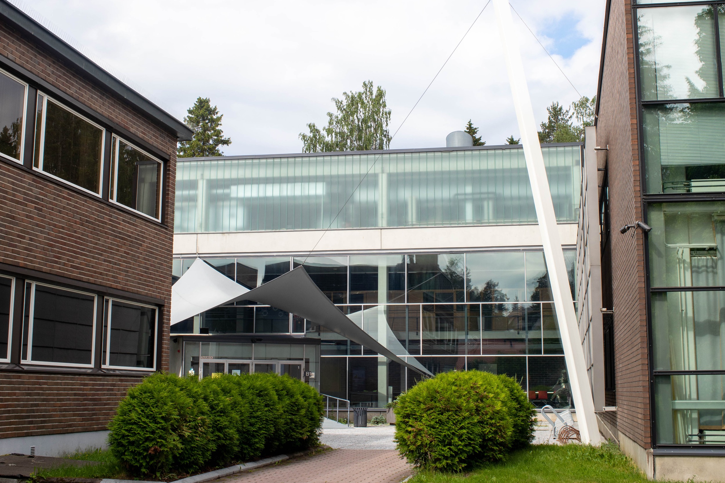 The front door of Riihimäki University of Applied Sciences. On top of the door is a large canvas. Multi-storey house, some walls with windows.