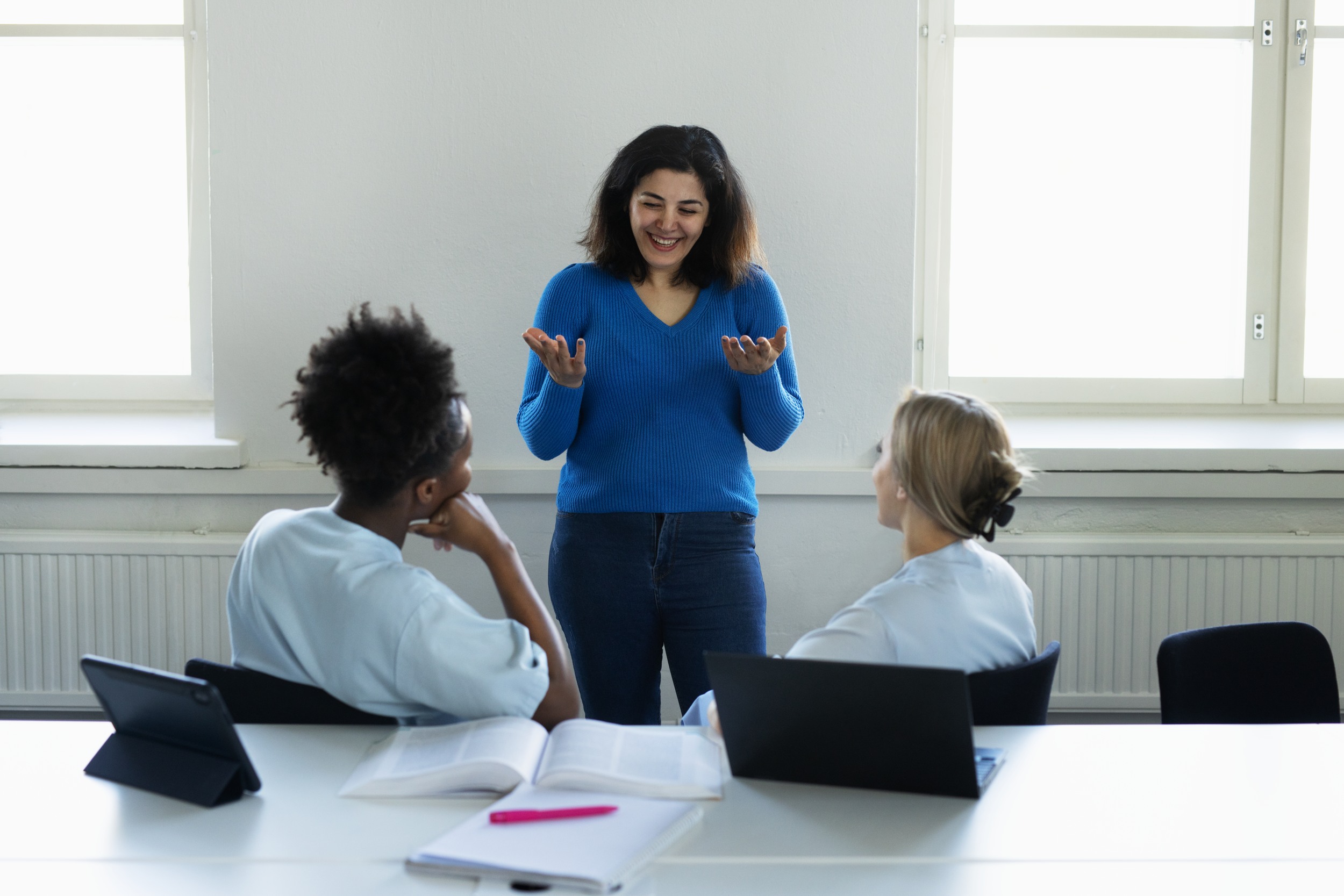 One woman standing and two sitting in front of her.