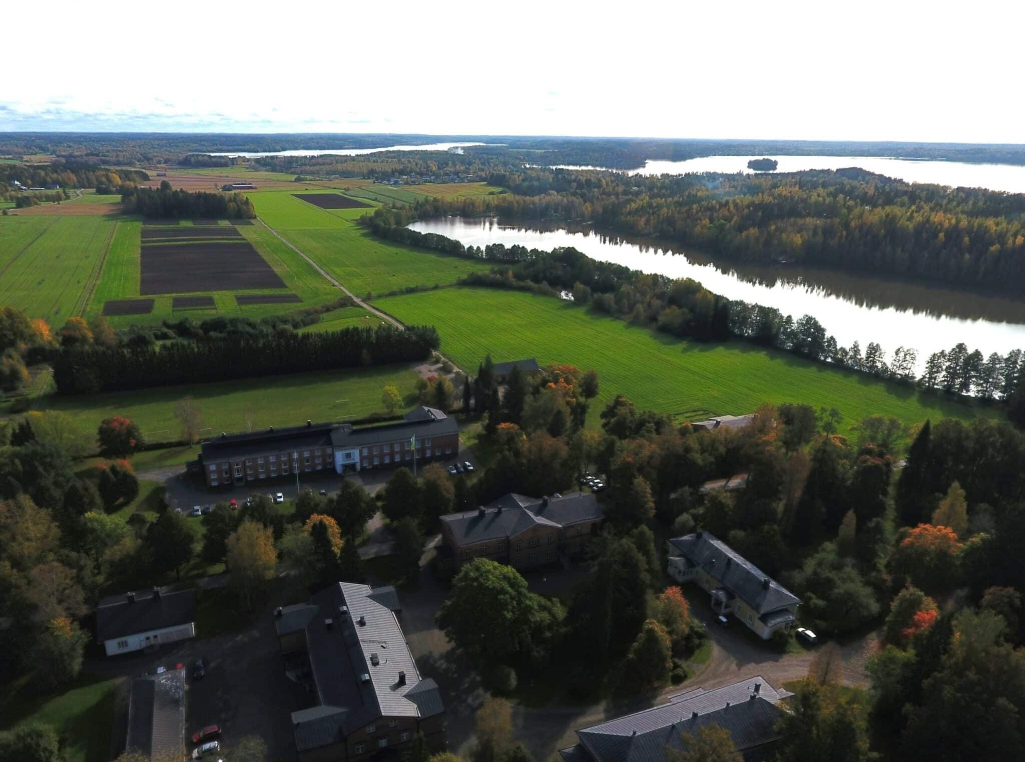 Ilmakuvaa kampukselta. Taustalla peltoa ja järvi.