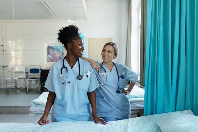 Kaksi sairaanhoitajaa seisoo vierekkäin ja katsoo toisiaan