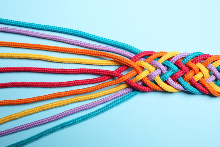 Braided colorful ropes on light blue background, top view. Unity concept