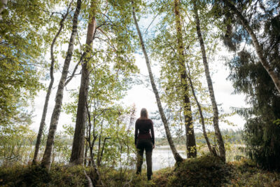 Nainen metsässä katsomassa järvelle/ Woman in the forest looking at a lake 