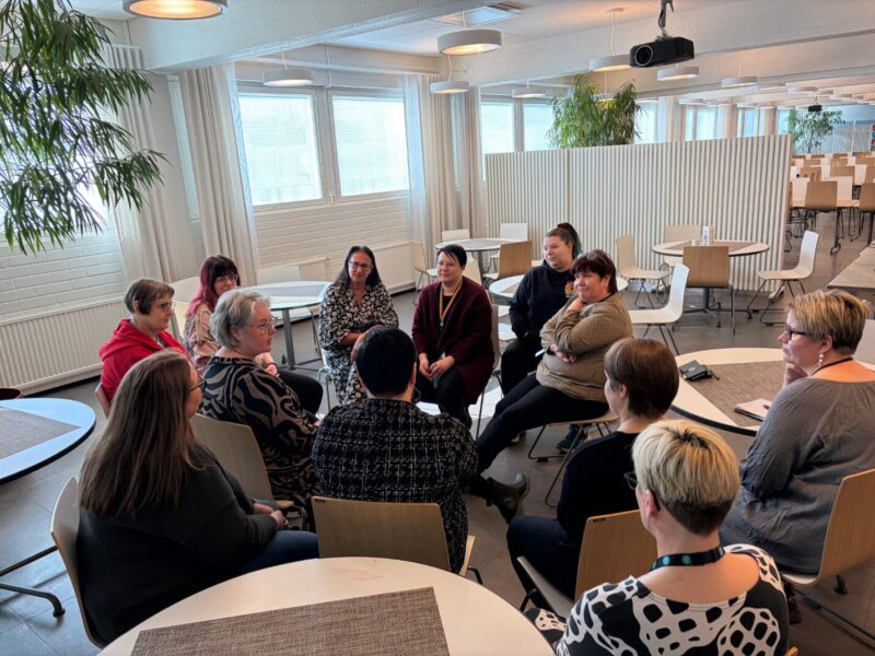 Joukko ihmisiä istuu ringissä keskustelemassa.