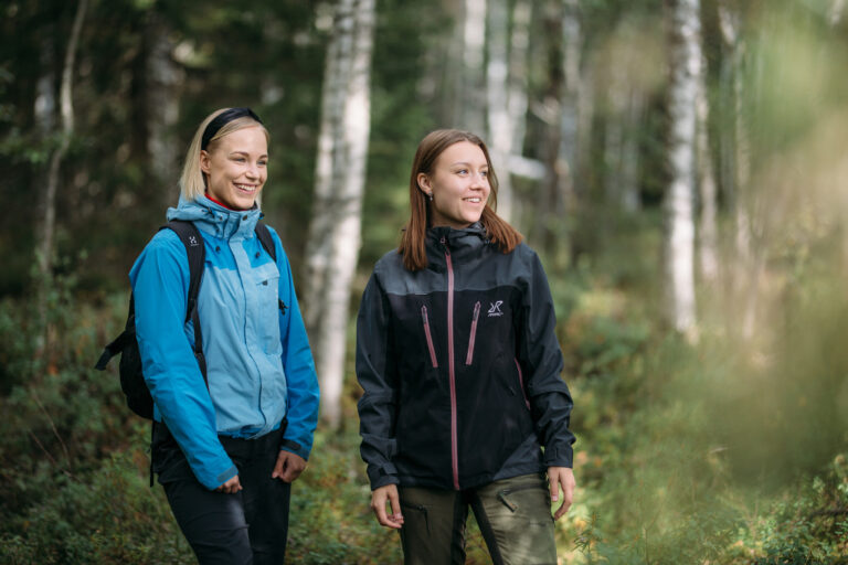 Two women smiling in a forest/Kaksi naista hymeyilee metsässä