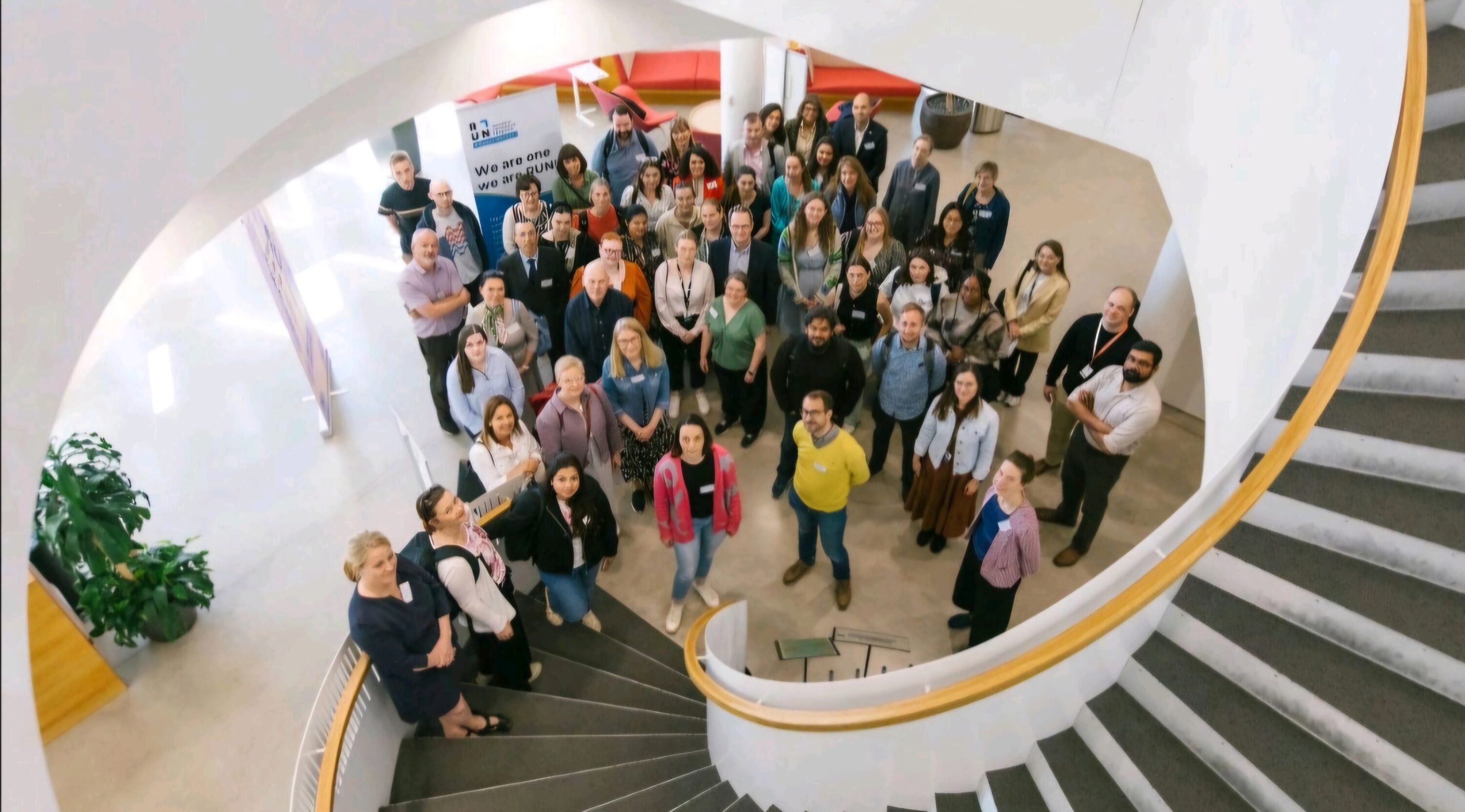 Ryhmä ihmisiä seisoo aulassa ja katsoo kameraan