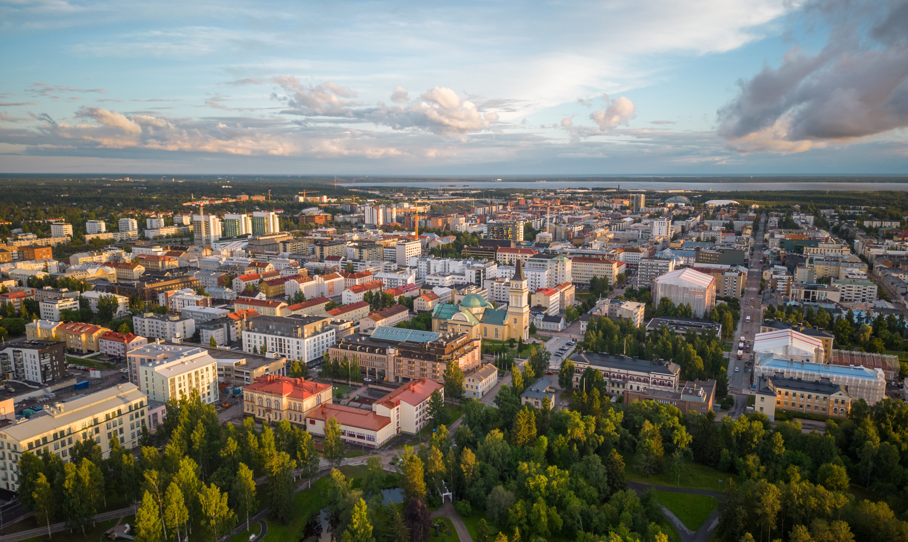 Kesäinen kaupunki ylhäältä päin kuvattuna. Paljon korkeita taloja ja jonkin verran metsää.