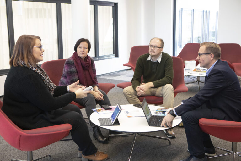 Ihmisiä keskustelemassa pöydän ääressä.