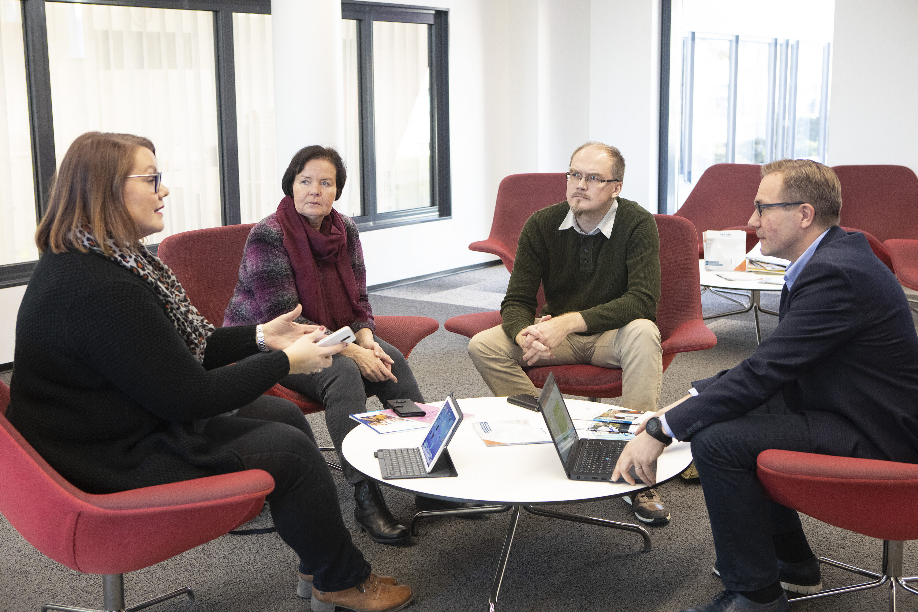 Ihmisiä keskustelemassa pöydän ääressä.