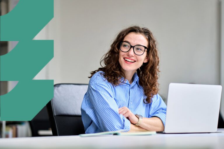 Hymyilevä nainen istuu tietokoneen ääressä.