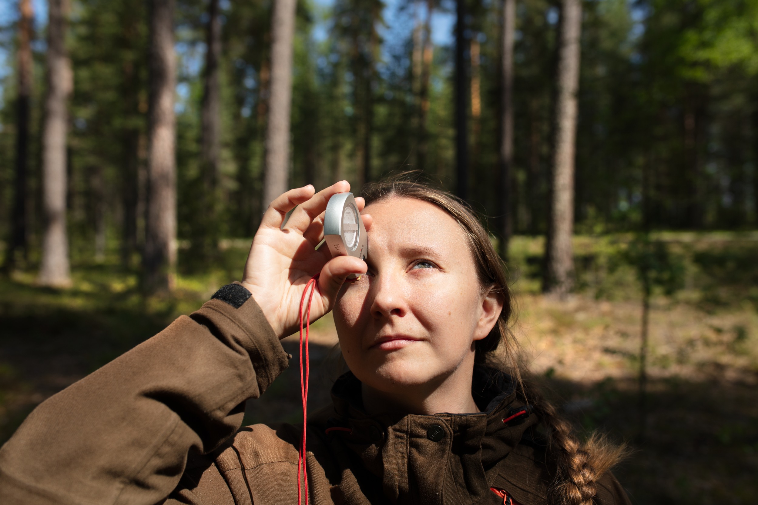 Nainen katsomassa optometrin läpi puiden latvoja
