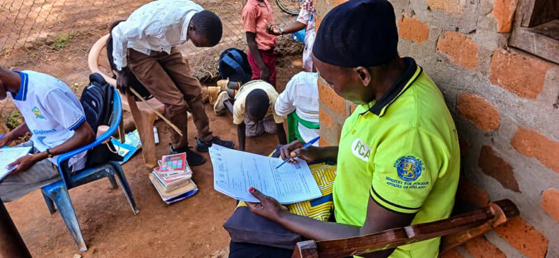 Ihmisiä istumassa kirjoittamassa paperille