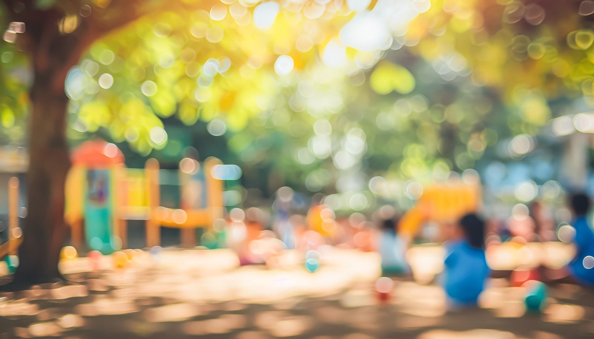 Epäterävä ulkokuva leikkipaikasta, jossa useita lapsia leikkii värikkäiden leikkivälineiden keskellä auringonpaisteisessa puistoympäristössä.