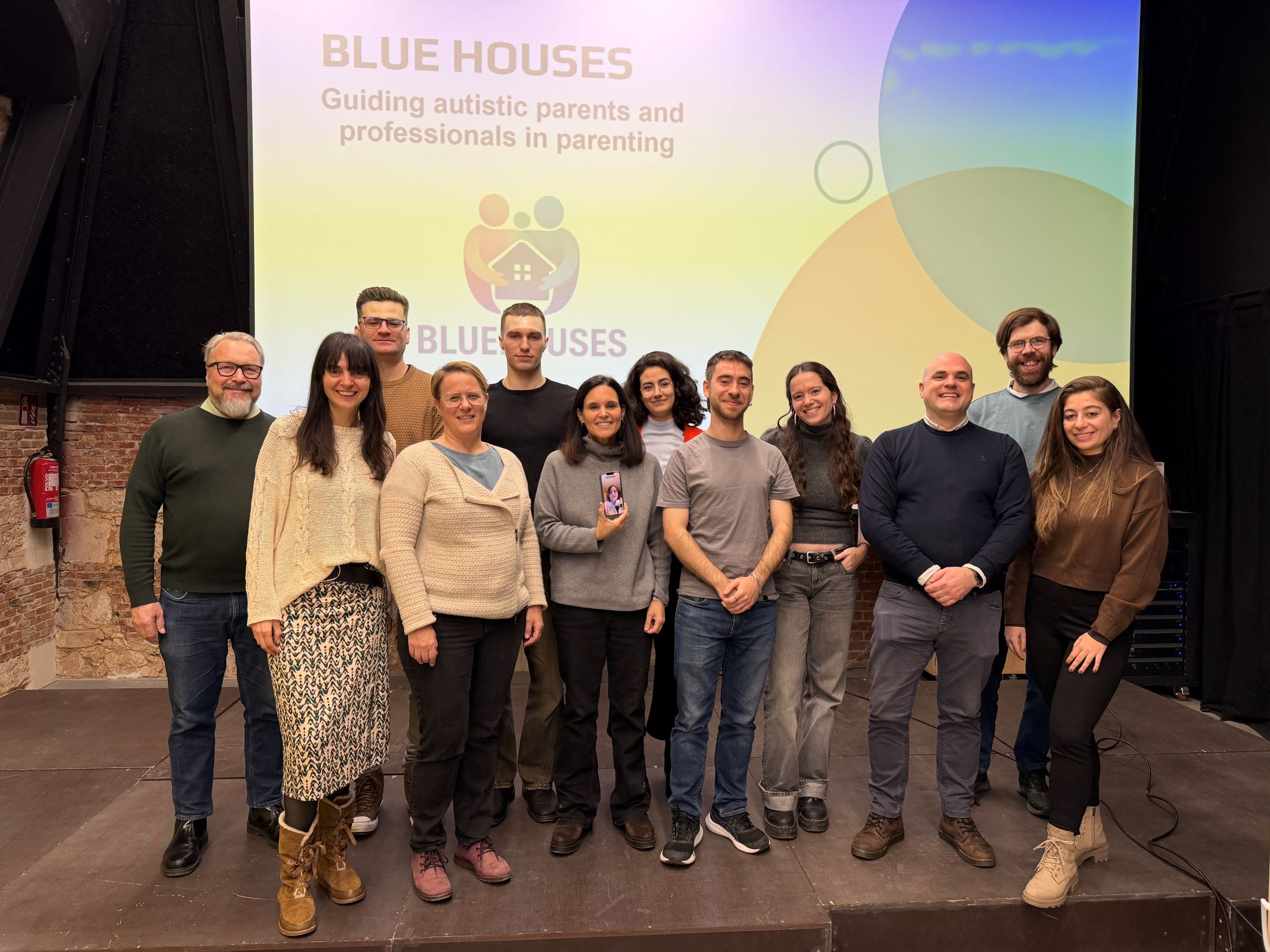Project members smiling at the camera in front of BLUEHOUSES sign