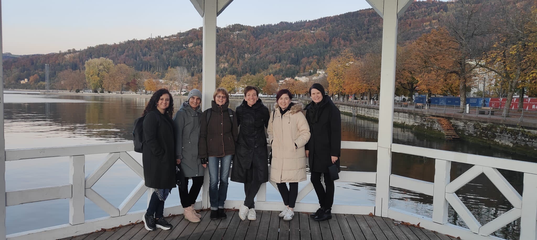 Kuusi henkilöä seisovat vierekkäin ja hymyilevät