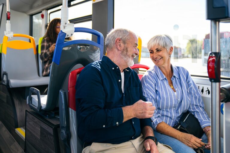 Senior couple traveling city bus together smiling