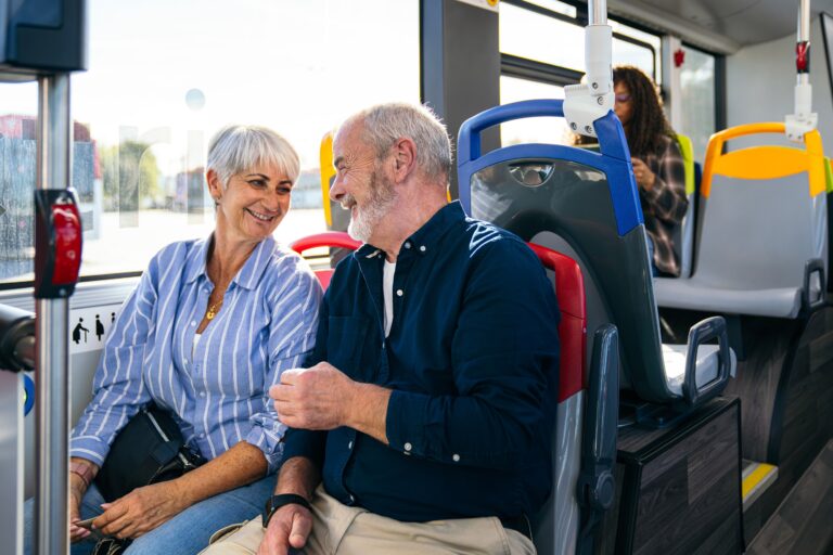 Senior couple traveling city bus together smiling