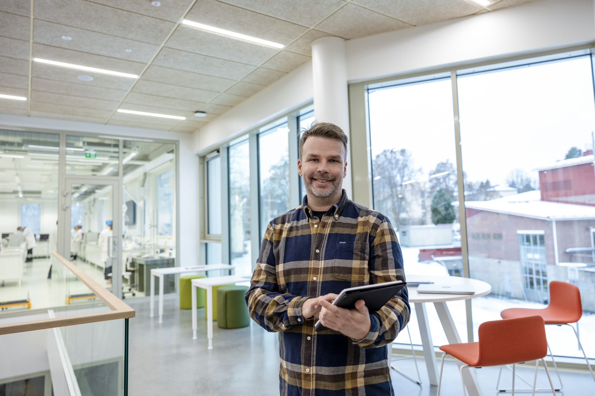 Mies seisoo huoneessa ja pitää kädessään tablettia.