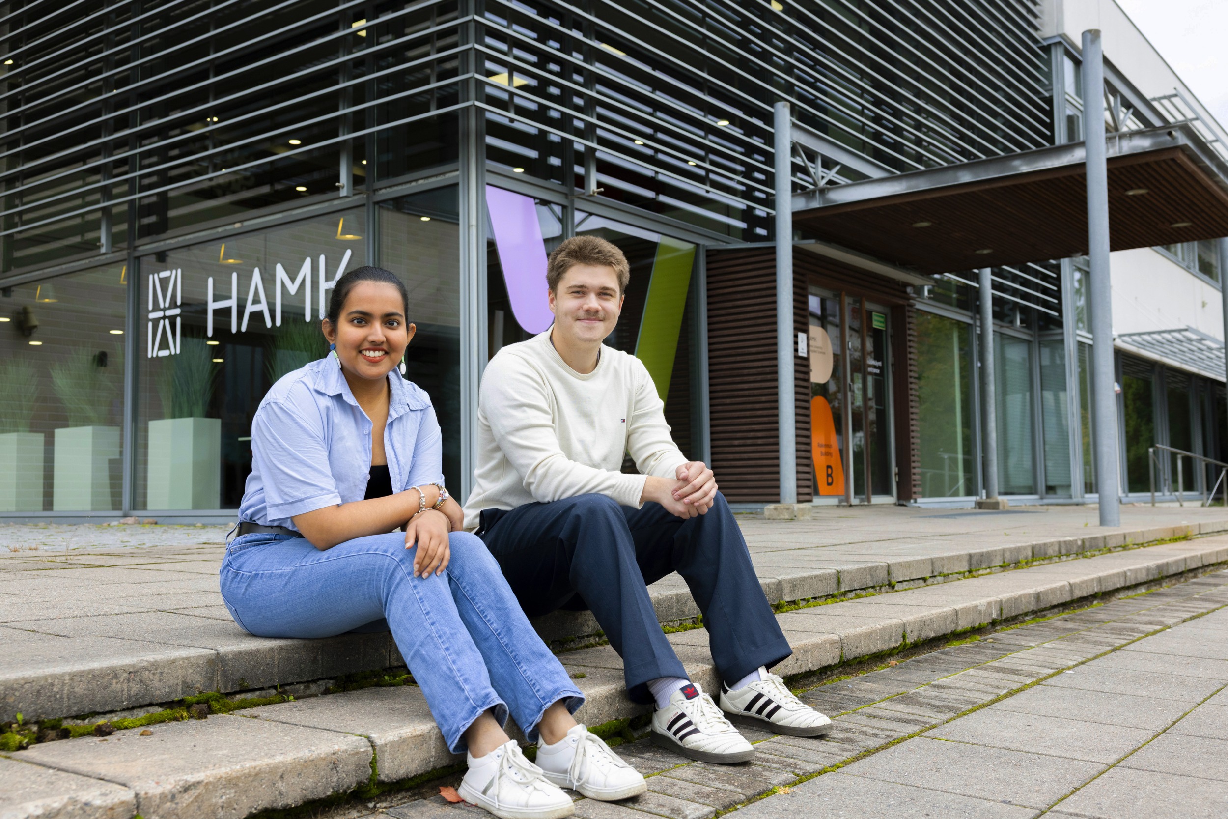 Kolme henkilöä istuu pöydän ääressä kampuksella.