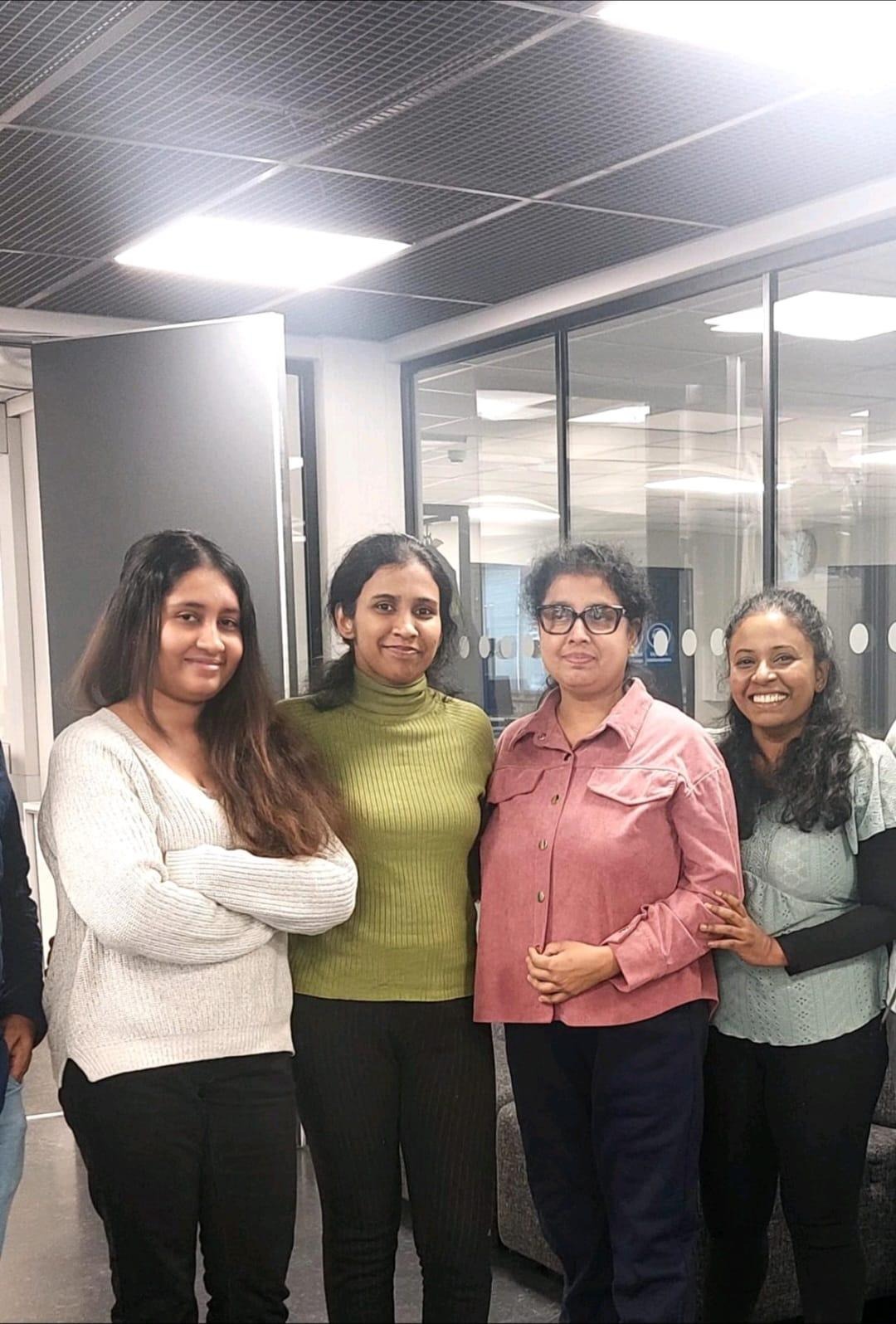 Neljä henkilöä seisovat ja katsovat kameraan