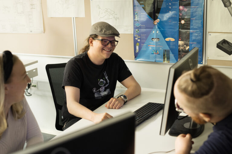 Kolme henkilöä tietokoneen äärellä / Three persons working at computer