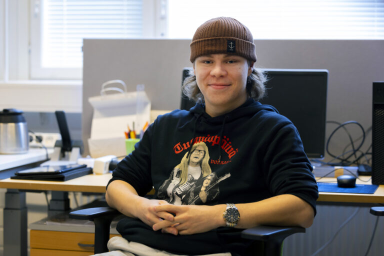 Nuori mies istuu toimistossa pipo päässä