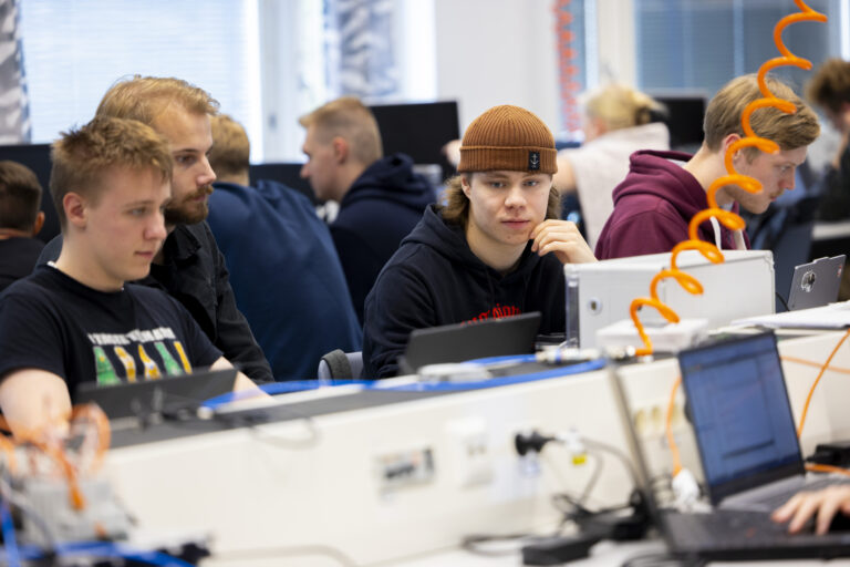 Ryhmä ihmisiä, jotka työskentelevät tietokoneilla huoneessa.