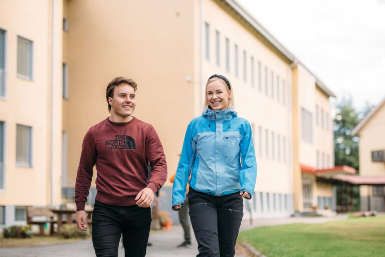 Two people walking outside of a building/ Kaksi ihmistä kävelee rakennuksen ulkopuolella