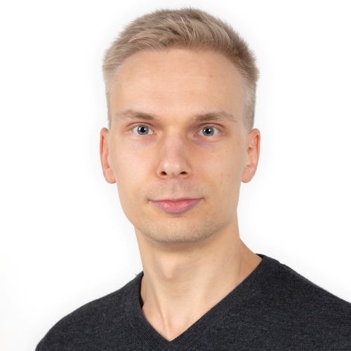 Henkilö, jolla musta paita ja vaaleat lyhyet hiukset, katsoo suoraan kameraan.