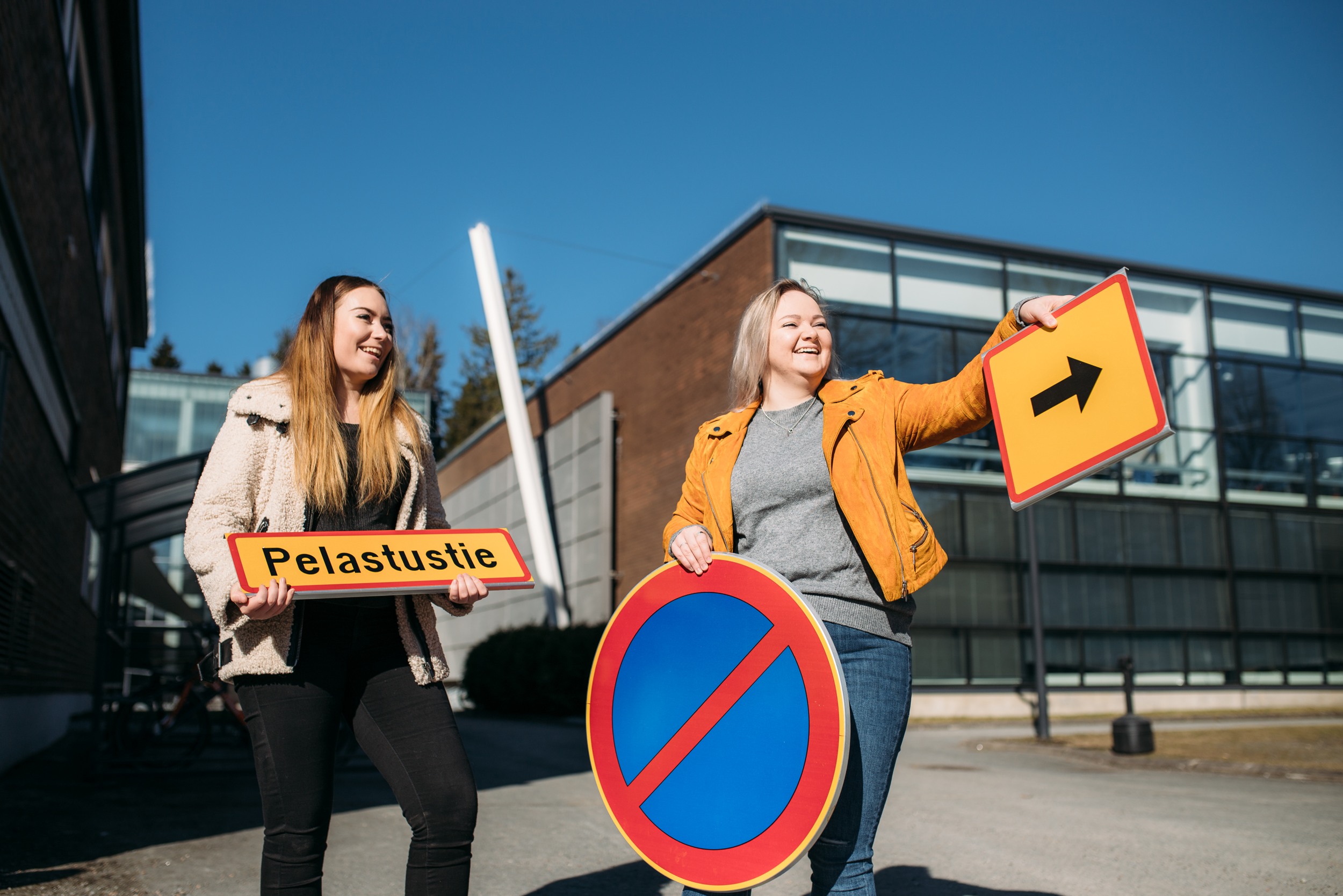 Kaksi liikennealan opiskelijaa opastekylttien kanssa.