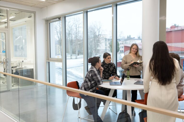 Neljä henkilöä tekemässä ryhmätyötä pöydän ääressä