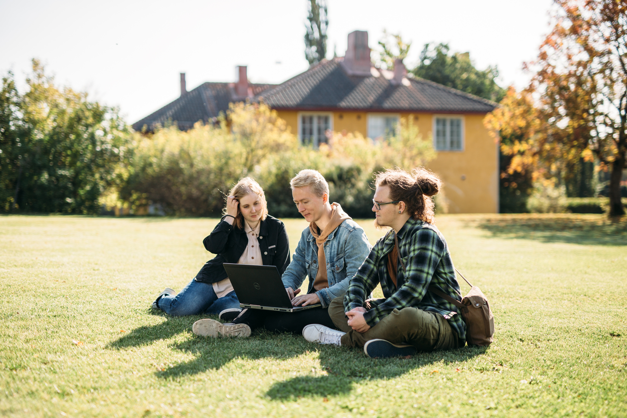 Kolme ihmistä istuu puutarhassa/ Three people sitting in a garden